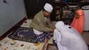 Seorang perempuan Thailand mencium tangan suaminya setelah salat di ruang tamu rumah mereka di Bangkok, 28 April 2020. Banyak tempat ibadah ditutup guna membendung penyebaran Virus Corona COVID-19 ketika Umat Muslim di seluruh dunia menyambut bulan suci Ramadan. (AP Photo/Gemunu Amarasinghe)
