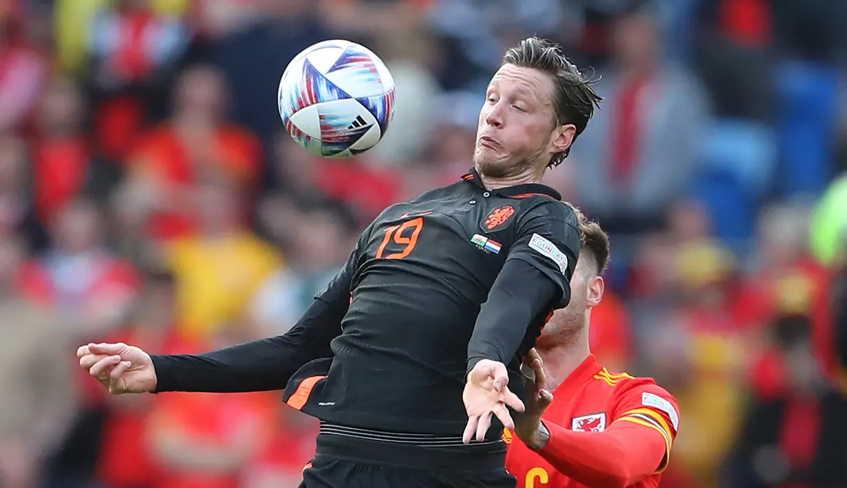 Striker Belanda, Wout Weghorst mengontrol bola dari kawalan bek Wales, Joe Rodon selama pertandingan grup A4 UEFA Nations League di stadion Cardiff City di Cardiff, Wales selatan, Kamis (9/6/2022). Belanda menang tipis atas Wales 2-1. (AFP/Geoff Caddick)