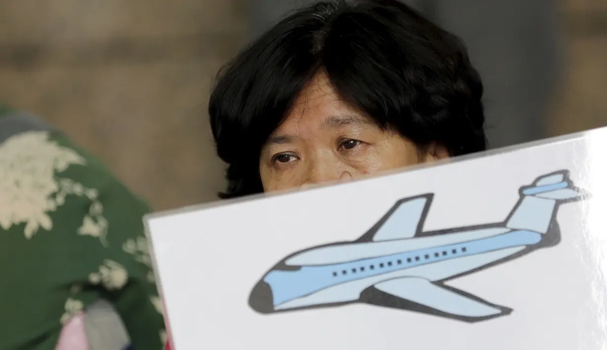 Salah satu keluarga penumpang MH370 membawa poster saat menggelar aksi di depan kantor Malaysia Airlines, Beijing, China, Kamis (6/8). Pemerintah Malaysia telah resmi menyatakan puing pesawat di Pulau Reunion adalah bagian dari MH370. (REUTERS/Jason Lee)