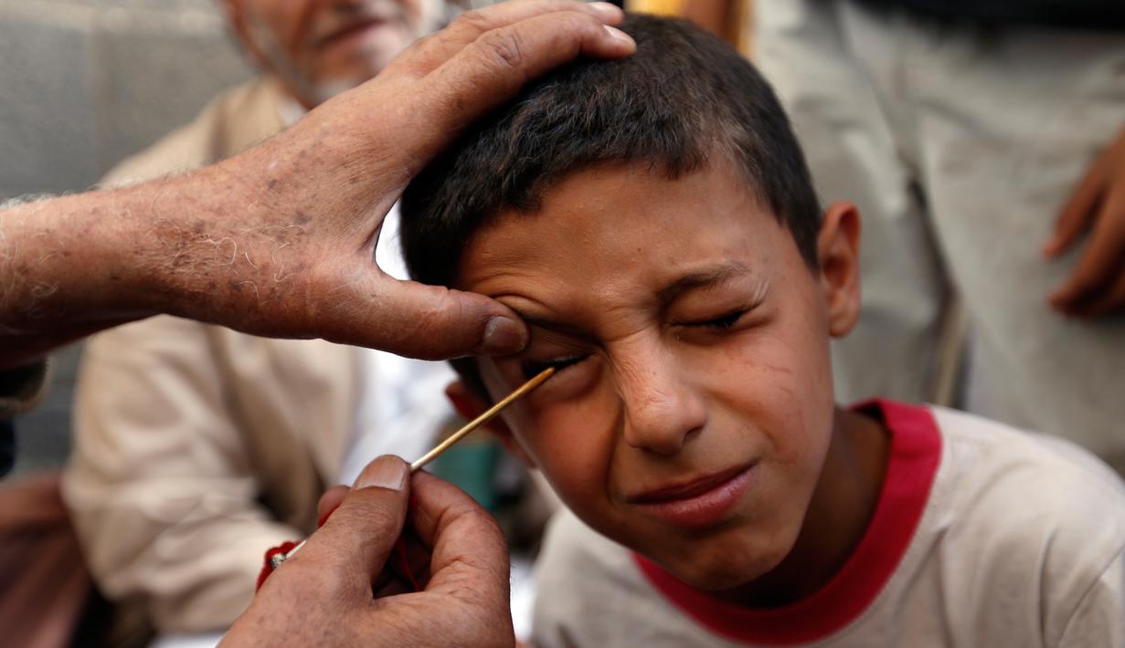 Seorang saat kelopak matanya dirias dengan kohl atau celak di  Masjid Agun di kota tua ibukota Sanaa, Yama, (19/5). Pemakaian kohl atau celak diyakini muslim Yaman mampu membersihkan dan melindungi mata dari penyakit. (AFP Photo/Mohammed Huvais)