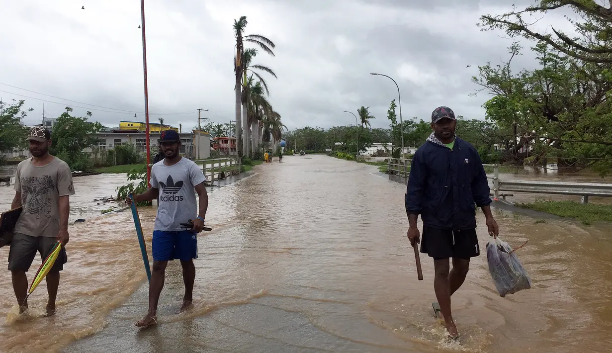 Warga berjalan melewati banjir di kota Ba, wilayah barat Fiji, Rabu (6/4). Zena, dengan kecepatan putaran angin hingga 120 kilometer per jam bergerak ke arah timur menuju Fiji. (NAZIAH ALI/MAI LIFE MAGAZINE /AFP)