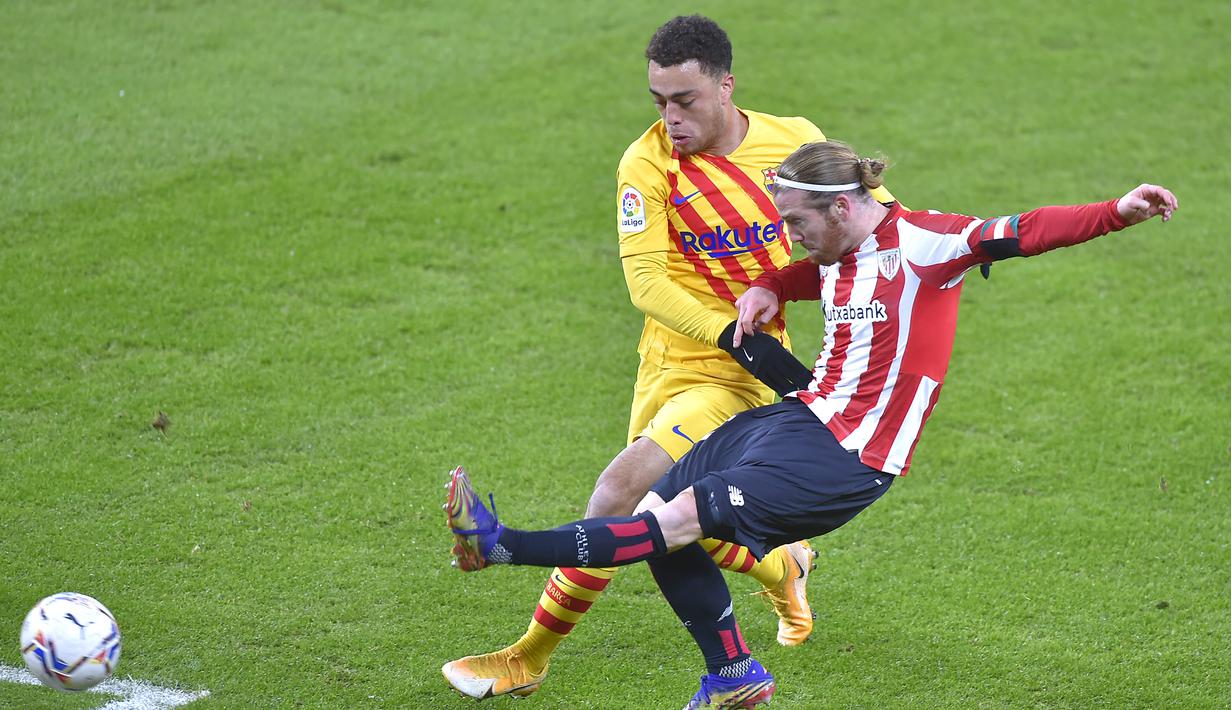 Striker Athletic Bilbao, Iker Muniain (kanan) melepaskan tendangan dibawah tekanan bek Barcelona, Sergino Dest dalam laga lanjutan Liga Spanyol 2020/21 di San Mames Stadium, Bilbao, Rabu (6/1/2021). Athletic Bilbao kalah 2-3 dari Barcelona. (AFP/Ander Gillenea)