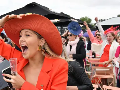 Seorang wanita bersorak saat menyaksikan balap kuda di Race 4 di Melbourne Cup di Flemington Racecourse di Melbourne, Australia, (7/11). Para wanita ini tampil cantik dengan hiasan kepala yang mereka gunakan. (AP Photo / Andy Brownbill)