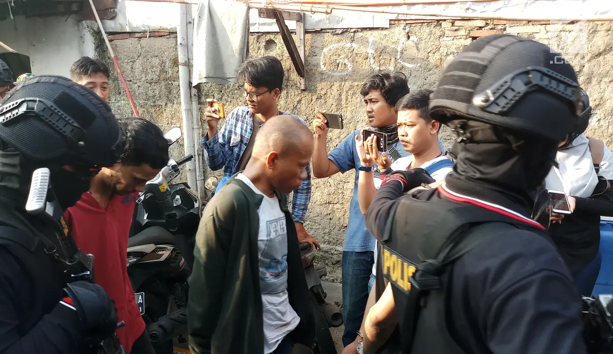 Petugas menggiring terduga pelaku dalam penggerebekan Kampung Boncos, Kota Bambu Selatan, Palmerah Jakarta Barat, Rabu (7/2). (Liputan6.com/ Ady Anugrahadi)