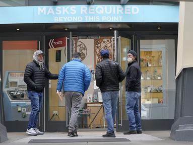 Orang-orang berjalan ke pintu masuk di Space Needle di bawah tanda bertuliskan "Masker Diperlukan" di Seattle pada 17 Februari 2022. Gubernur Jay Inslee mengatakan mandat masker dalam ruangan di negara bagian Washington akan dicabut pada 21 Maret 2022 mendatang. (AP Photo/Ted S. Warren)