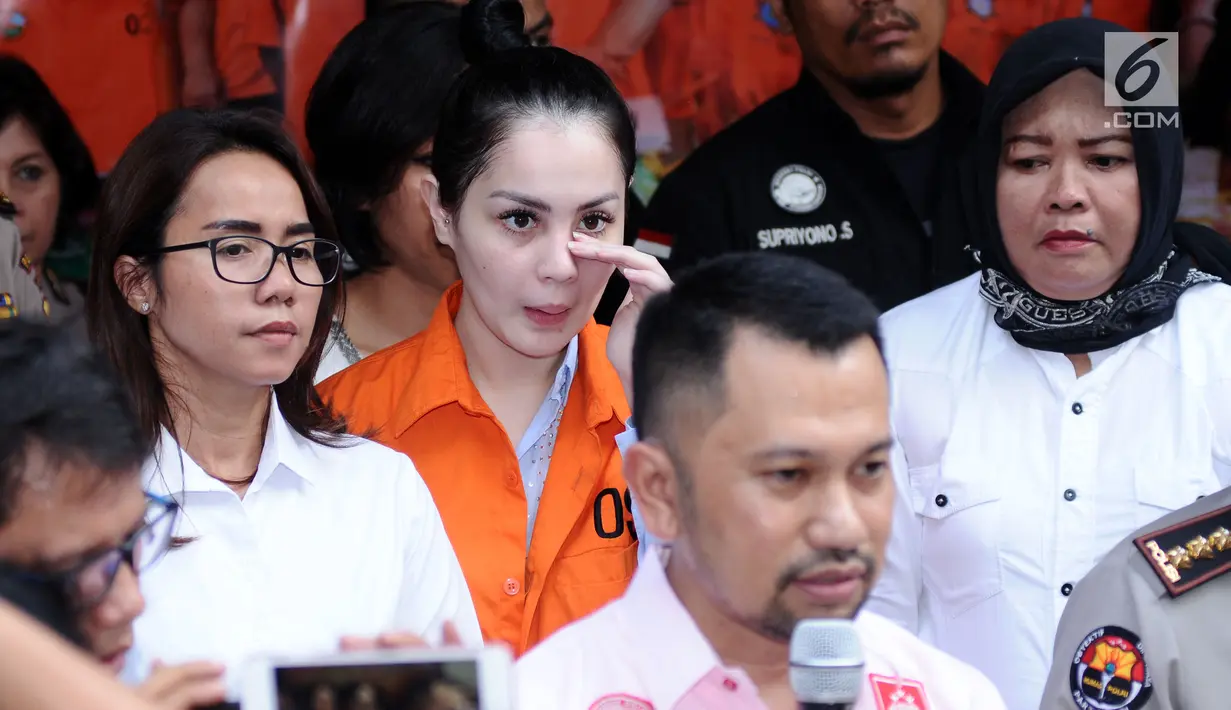Artis peran dan model, Jennifer Dunn mengusap wajah saat diperlihatkan usai penangkapan di Dirnarkoba Polda Metro Jaya, Jakarta, Selasa (2/1). Sebelumnya ia ditangkap polisi sebanyak dua kali, pada 2005 dan 2009 silam. (Liputan6.com/Helmi Fithriansyah)