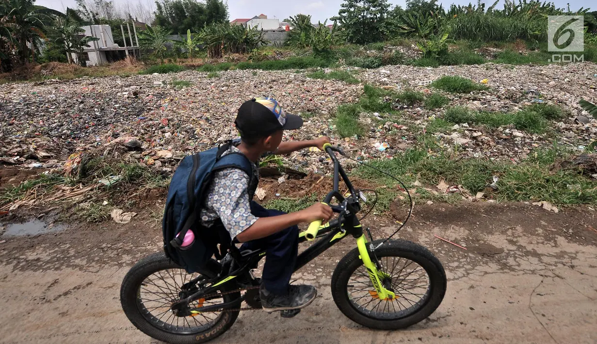 Anak sekolah melintas di pinggir Kali Pisang Batu yang dipenuhi sampah, Tarumajaya, Bekasi, Jawa Barat, Rabu (9/1). Warga tetap beraktivitas meski bau tak sedap menghantui mereka akibat tumpukan sampah di kali tersebut. (Merdeka.com/Iqbal S. Nugroho)