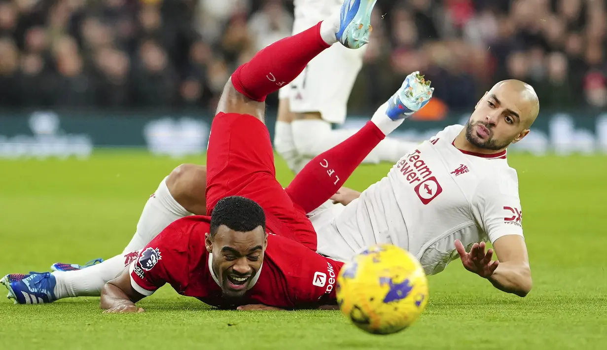 Pemain Liverpool, Ryan Gravenberch (kiri) tersungkur setelah berebut bola dengan pemain Manchester United, Sofyan Amrabat pada laga lanjutan Liga Inggris 2023/2024 di Anfield, Liverpool, Inggris, Rabu (18/12/2023) dini hari WIB. (AP Photo/Jon Super)