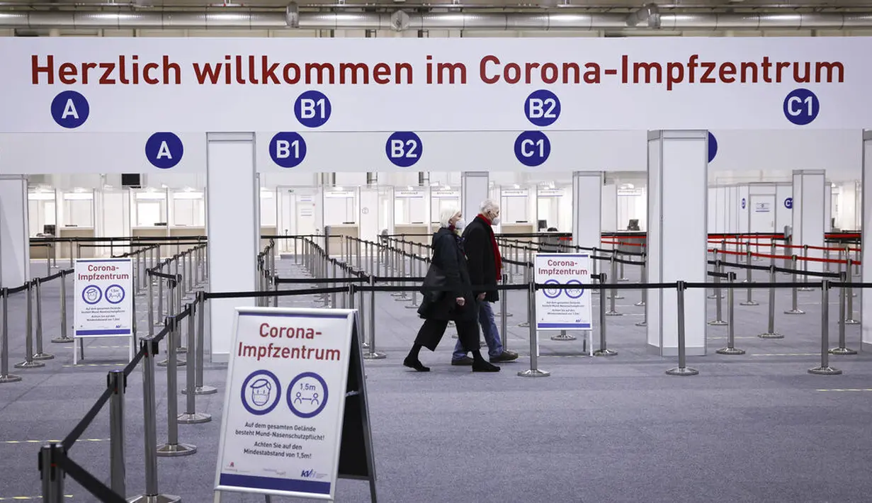 Dua lansia jalan melewati Pusat Imunisasi di Ruang Pameran untuk vaksinasi mereka di Hamburg, Jerman, Selasa (5/1/2021). Kementerian Kebudayaan Jerman mengatakan pembukaan kembali kegiatan belajar mengajar tatap muka hanya akan dilakukan ketika lockdown dilonggarkan. (Christian Charisius/dpa via AP)