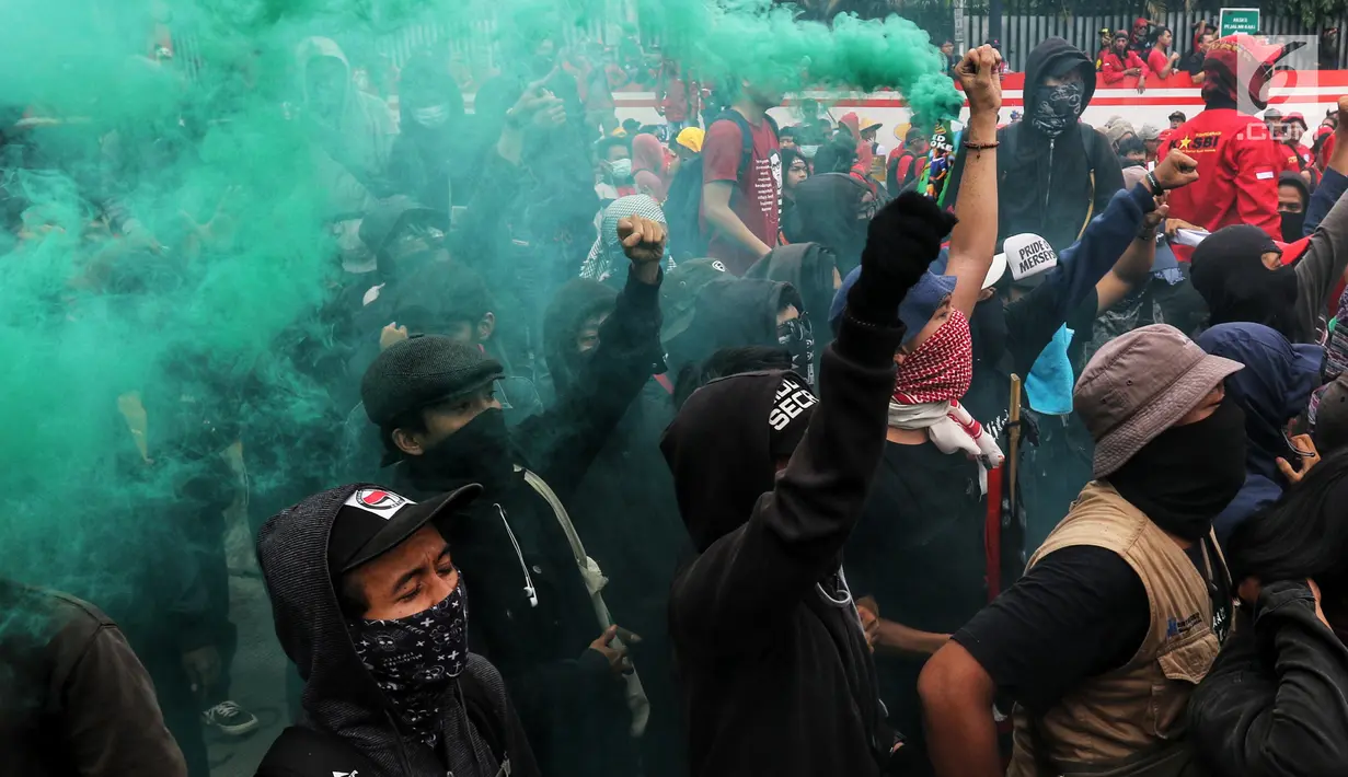 Peserta aksi dari berbagai serikat buruh menyalakan suar atau flare dalam peringatan Hari Buruh 2019 di Jalan Jenderal Sudirman dekat Bundaran HI, Jakarta, Rabu (1/5/2019). Massa sempat terlibat aksi saling dorong dengan barisan polisi agar bisa masuk menuju Bundaran HI. (Liputan6.com/Johan Tallo)