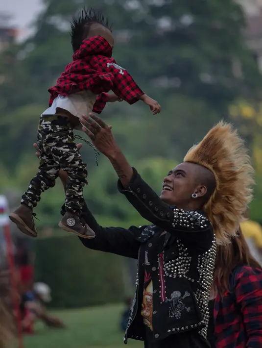Anggota anak punk bermain dengan anaknya yang berusia satu tahun saat ia dan beberapa temannya berkumpul di sebuah taman di Yangon (12/4). Masyarakat Myanmar merayakan Festival Thingyan atau festival air. (AFP Photo / Roberto Schmidt)