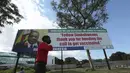 Seorang anak laki-laki berjalan melewati papan reklame dengan pesan dari Presiden Zimbabwe Emmerson Mnangagwa berterima kasih kepada orang-orang karena mengindahkan seruan untuk divaksinasi di Harare, Zimbabwe, Senin (29/11/2021). (AP Photo/Tsvangirayi Mukwazhi)