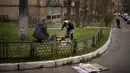 Lyubov Lomachuk (69) memasak makan siang untuk keluarga dan tetangganya di atas api darurat di taman umum dekat rumahnya di Bucha, pinggiran Kiev, Senin (18/4/2022). Warga Bucha masih tanpa listrik, air dan gas setelah lebih dari 43 hari sejak invasi Rusia. (AP Photo/Emilio Morenatti)