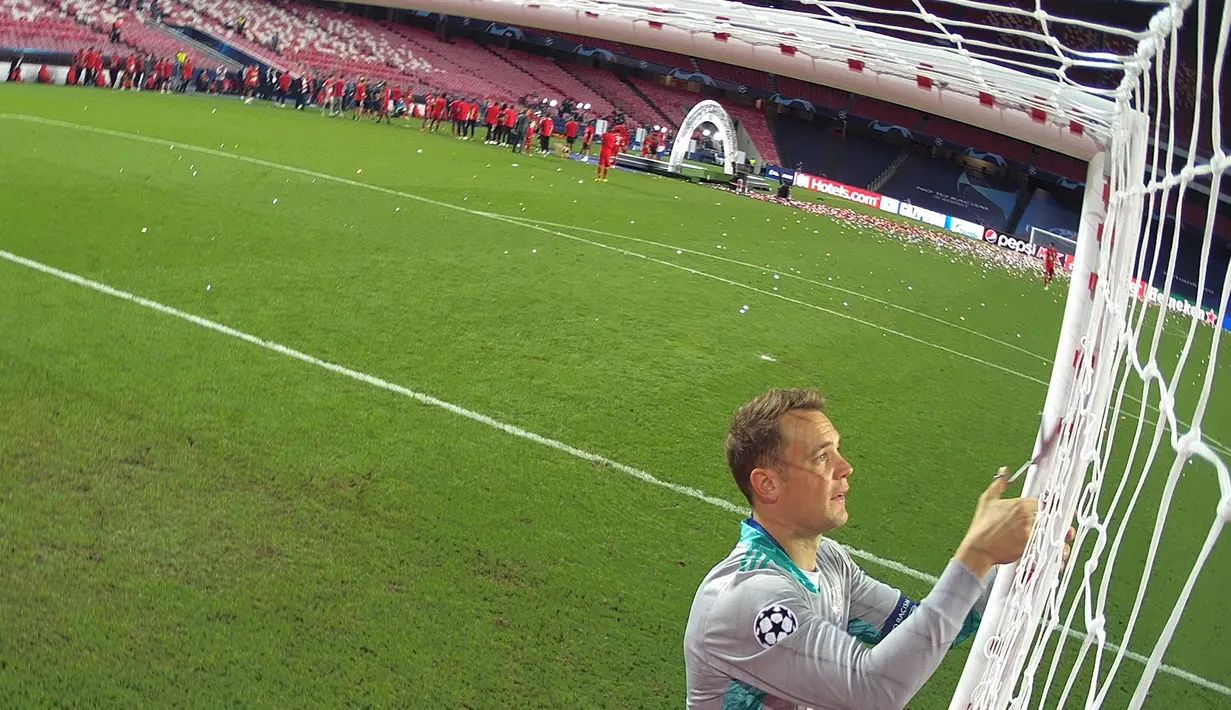 Kiper Bayern Munchen, Manuel Neuer memotong jaring gawang saat merayakan timnya meraih trofi Liga Champions usai mengalahkan PSG pada pertandingan final di stadion Luz di Lisbon (23/8/2020). Munchen menang tipis atas PSG 1-0. (AFP/Lluis Gene)