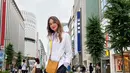 Berlibur di Jepang, Luna Maya tampil berbeda memadukan dua kemeja sekaligus. Ia memadukan kemeja dengan motif striped warna ungu dan putih dengan kemeja berwarna putih polos sebagai outer. Atasannya itu dipadukan dengan celana berwarna hitam, flat shoes, serta sling bag warna kuning, (Instagram/lunamaya).