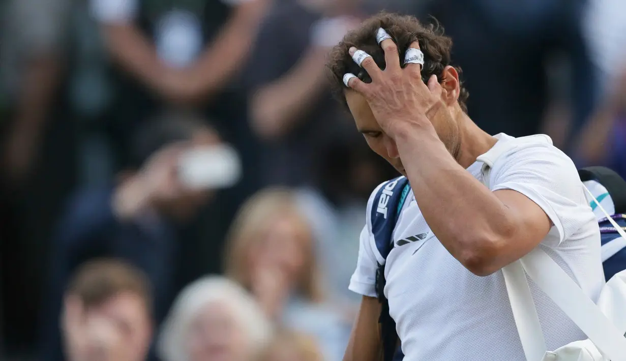 Petenis Spanyol, Rafael Nadal, mengusap rambutnya sambil meninggalkan lapangan setelah dikalahkan Giller Muller (Luksemburg) di perempat final Wimbledon 2017, Senin (10/7). Nadal menyerah dari Mueller usai melewati pertarungan lima set. (AP/Tim Ireland)