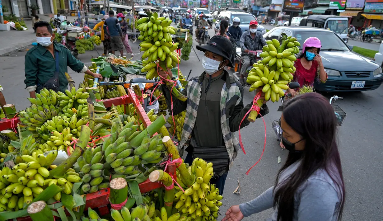 Seorang wanita membeli pisang di sepanjang jalan di Phnom Penh 13/10/2021). Tiga spesies pisang  kuning, gula dan hijau semuanya banyak ditanam di Kamboja. (AFP/Tang Chhin Sothy)