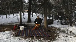 Seorang pria sedang piknik saat menghabiskan akhir pekannya di taman yang tertutup salju, di Teheran utara, Iran, Jumat (25/12/2020). Musim dingin di Iran biasanya dimulai dari bulan Desember hingga Februari.  (AP Photo/Vahid Salemi)