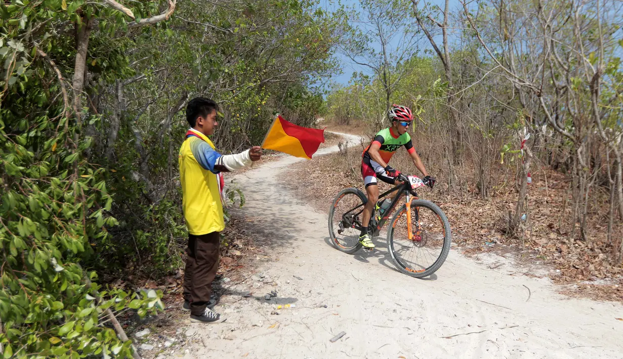 Seorang anggota Pramuka menjadi Marshall saat pebalap mengikuti Mountain Bike Cross Country Marathon pada Festival Pesona Tanjung Lesung 2017 di Tanjung Lesung, Banten (23/9/2017). MTB XCM tersebut menempuh jarak 48 km. (Bola.com/Nicklas Hanoatubun)