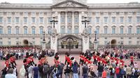 Orang-orang menyaksikan menyaksikan Band of The Coldstream Guards berbaris selama upacara Pergantian Penjaga di Istana Buckingham, London, yang berlangsung untuk pertama kalinya sejak dimulainya pandemi corona Covid-19 pada Senin (23/8/2021). (Kirsty O'Connor/PA via AP)