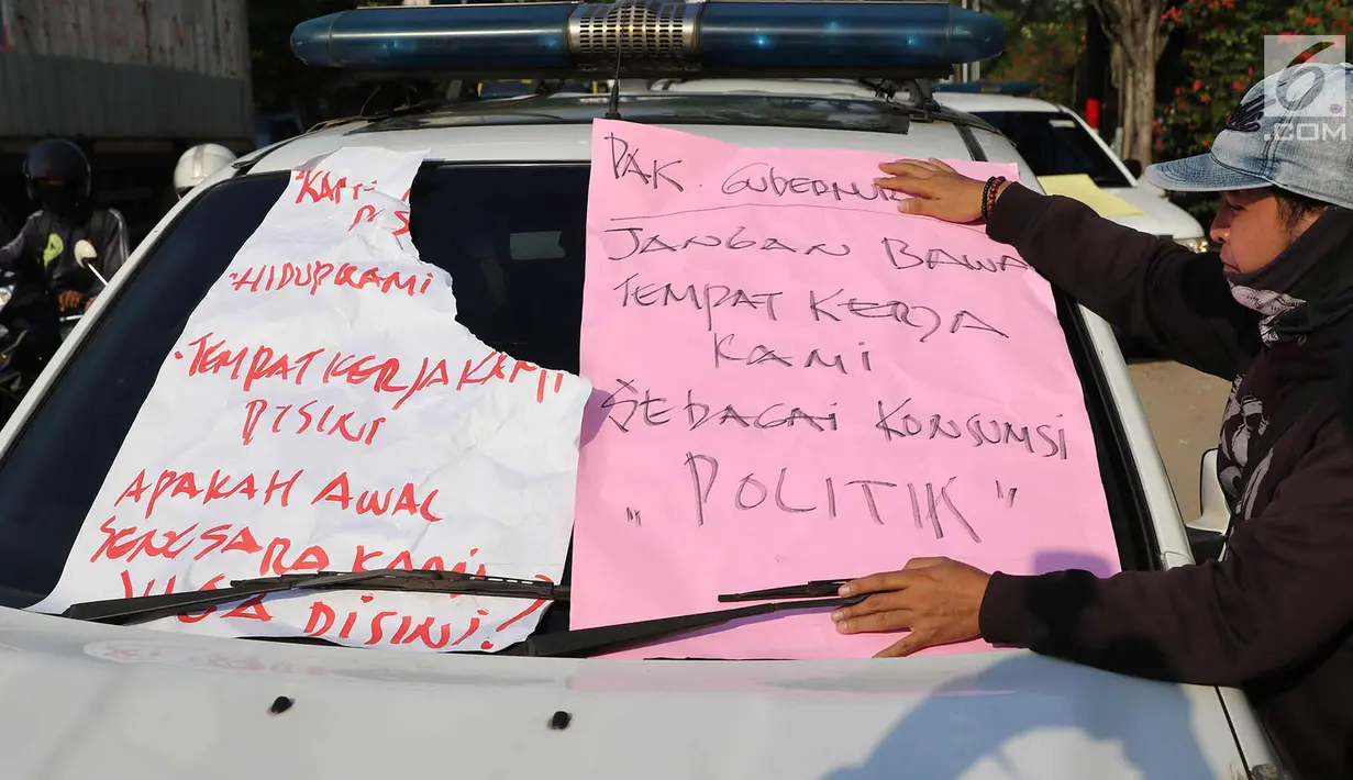 Karyawan Hotel Alexis menempelkan poster tuntutan di mobil Satpol PP saat unjuk rasa di Jakarta Utara, Kamis (29/3). Penutupan terkait kasus dugaan adanya praktek prostitusi dan perdagangan manusia di hotel tersebut. (Liputan6.com/Immanuel Antonius)