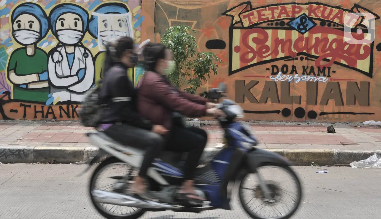 Pengendara melintas di depan mural dukungan untuk tim medis Covid-19 di kawasan Sunter, Jakarta, Rabu (27/5/2020). Mural tersebut sebagai bentuk dukungan untuk tim medis penanganan Covid-19 sekaligus mengingatkan masyarakat agar taat mengikuti aturan PSBB. (merdeka.com/Iqbal S. Nugroho)