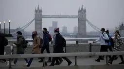 Pekerja berjalan di atas Jembatan London menuju distrik keuangan Kota London, dengan latar belakang Tower Bridge, pada jam sibuk pagi hari, Senin (24/1/2022). Inggris telah meminta orang-orang untuk kembali bekerja di kantor saat mereka melonggarkan pembatasan corona COVID-19. (AP Photo/Matt Dunham)