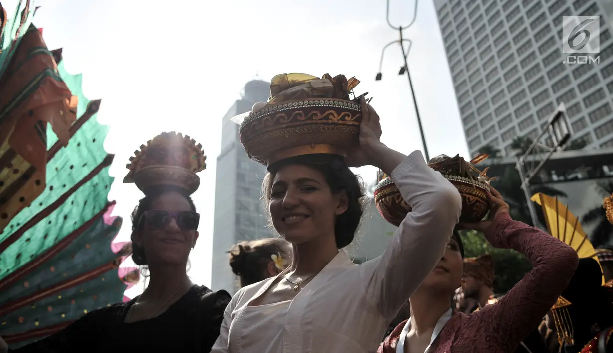 Senyum mahasiswa internasional dengan balutan pakaian adat Indonesia membawa berbagai macam rempah-rempah di kepalanya saat pawai kelulusan beasiswa Kemendikbud di car free day (CFD), Jakarta, Minggu (6/5). (Merdeka.com/Iqbal Nugroho)