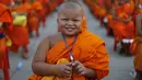 Seorang Biksu Buddha tersenyum saat menunggu acara penerimaan sedekah di kuil Wat Phra Dhammakaya, Bangkok, Thailand, (22/4). Kegiatan ini juga sebagai penasbihan para bhikkhu dan samanera atau calon Biksu. (REUTERS / Jorge Silva)