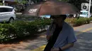 Pejalan kaki mengenakan payung untuk menghindari panas matahari di kawasan Kuningan, Jakarta, Selasa (26/9/2023). (merdeka.com/Imam Buhori)