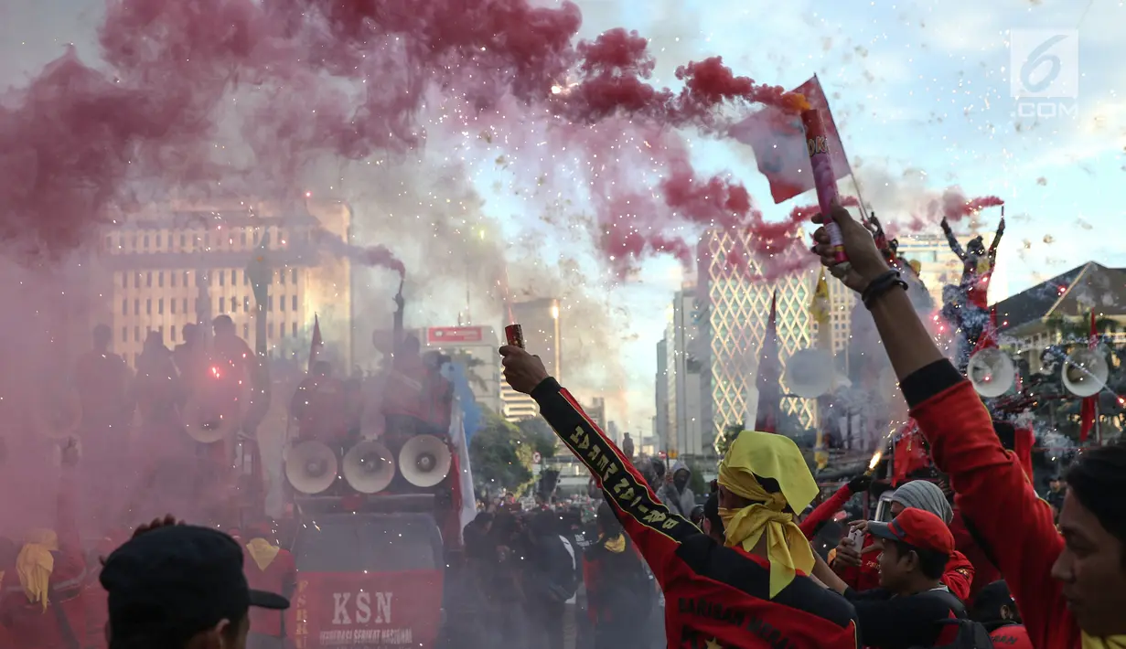 Sejumlah buruh menyalakan bom asap saat menutup aksi Hari Buruh Internasional di Jalan Medan Merdeka Barat, Jakarta, Rabu (5/1/2019). Buruh dari berbagai organisasi merayakan Hari Buruh Internasional di Kawasan Silang Barat Daya Monas. (Liputan6.com/Helmi Fithriansyah)