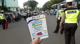 Petugas Dinas Perhubungan menunjukkan selebaran sosialisasi pemberlakuan sistem ganjil genap di pintu masuk Gardu Tol Cibubur 2, Jakarta, Senin (16/4). Aturan ini berlaku untuk kendaraan pribadi atau golongan I dan II. (Liputan6.com/Faizal Fanani)