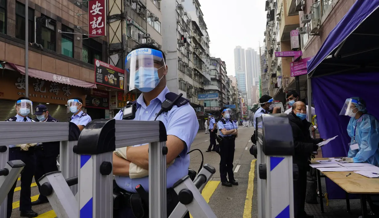 Petugas polisi berjaga di daerah Yau Ma Tei di Hong Kong, Sabtu (23/1/2021). Warga Hong Kong akan dilarang meninggalkan apartemen mereka kecuali dapat menunjukkan hasil negatif tes COVID-19 di mana dalam beberapa hari terakhir mengalami lonjakan kasus. (AP Photo/Vincent Yu)