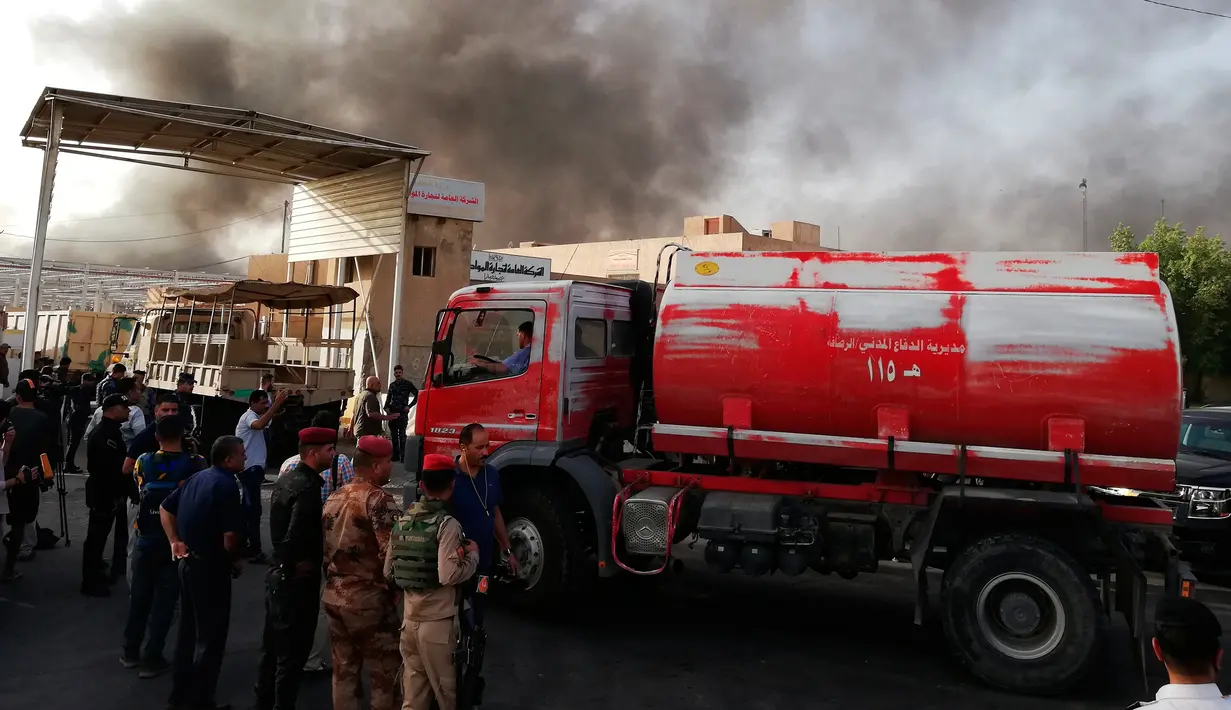 Pasukan keamanan dan pemadam berkumpul di lokasi kebakaran gudang surat suara terbesar Irak di Baghdad, Minggu (10/6). Gudang itu dilalap api sebelum dilakukan penghitungan kembali surat suara sebagaimana yang diperintahkan Parlemen. (AP/Karim Kadim)