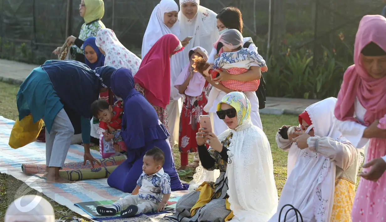 Penyanyi Syahrini memainkan ponselnya sebelum melaksanakan salat Idul Adha 1437 H di taman Tanah Sereal, Bogor, Senin (12/9). Syahrini memakai baju muslim bermotif, dilengkapi dengan luaran warna putih plus kacamata hitam. (Liputan6.com/Herman Zakharia)