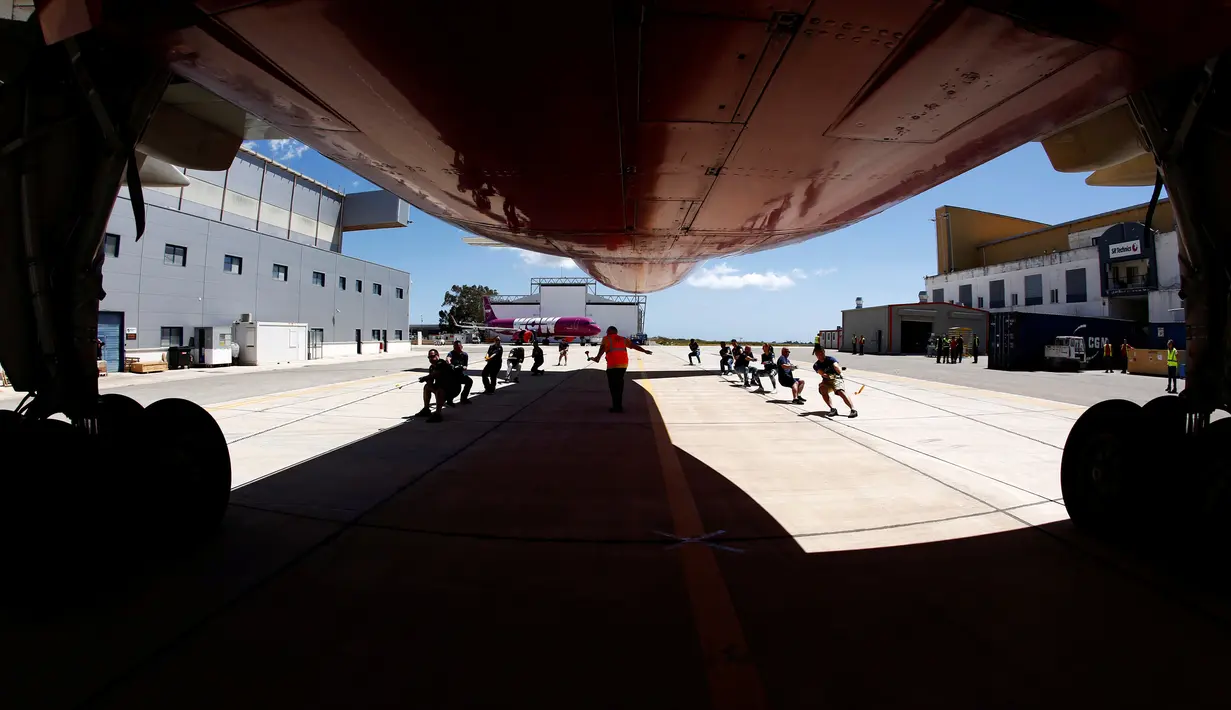 Anggota tim sekuat-tenaga untuk menarik pesawat DHL Boeing 757 sejauh 20 meter di Safi Aviation Park, Malta pada 1 Mei 2019. Kegiatan tarik pesawat tersebut merupakan rangkaian dalam rangka untuk penggalangan dana amal. (REUTERS/Darrin Zammit Lupi)