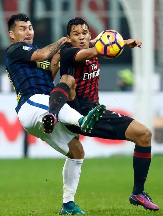 Penyerang AC Milan, Carlos Bacca berebut bola dengan gelandang Inter Milan, Gary Medel pada Liga Italia di Stadion San Siro, Milan, (20/11). AC Milan bermain imbang dengan Inter Milan dengan skor 2-2. (REUTERS/Alessandro Garofalo)