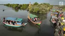 Perahu wisata melintasi kerumunan wisatawan yang berjalan di atas Jembatan Cinta di Wisata Mangrove, Tarumajaya, Bekasi, Minggu (30/12). Wisata tersebut berbatasan langsung dengan kawasan Marunda Jakarta Utara. (merdeka.com/Arie Basuki)