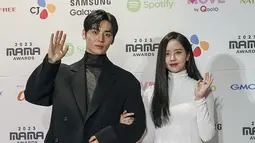 Hwang Minhyun mengenakan setelan jas berwarna hitam yang dipadukan dengan celana panjang berwarna senada. Sementara Kim So Hyun memakai long dress berwarna putih dengan model turtle neck. (Foto: AP Photo/Toru Hanai)