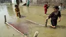 Anak-anak menyelamatkan sebuah ranjang bayi dari rumah mereka yang terkena banjir, di Charsadda, Pakistan, Rabu (31/8/2022). Para pejabat di Pakistan menyampaikan kekhawatiran Rabu atas penyebaran penyakit yang ditularkan melalui air di antara ribuan korban banjir saat air banjir dari hujan monsun yang kuat mulai surut di banyak bagian negara. (AP Photo/Mohammad Sajjad)