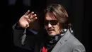 Aktor Johnny Depp memakai kacamata hitam dan syal saat menghadiri sidang pencemaran nama baik di Pengadilan Tinggi, London, Inggris, Selasa (21/7/2020). Johnny Depp menggugat tabloid The Sun atas artikel yang menyebut dirinya telah melakukan kekerasan terhadap sang istri. (AP Photo/Frank Augstein)