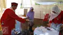 Petugas KPPS mengenakan pakaian ala Betawi mempersilahkan  pemilih untuk mencelupkan jarinya ke tinta di TPS 31/32, Kelurahan Pondok Benda, Tangerang Selatan, Rabu (9/12). Pilkada Kota Tangsel ini diikuti tiga pasangan calon. (Liputan6.com/Fery Pradolo)