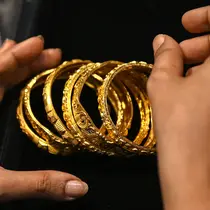 Gambar diambil pada 11 Agustus 2021 menunjukkan seorang pelanggan memegang gelang emas di sebuah toko perhiasan di Mumbai, India. Putus asa mendapatkan uang tunai, banyak keluarga dan usaha kecil menjual perhiasan emas sebagai jaminan untuk mendapatkan pinjaman jangka pendek. (Punit PARANJPE/AFP)