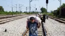 Seorang anak berjalan dengan membawa barang menyusuri rel kereta api saat perjalanan menuju Gevgelija, wilayah perbatasan Macedonia-Yunani, Kamis (9/7/2015). Mereka mencari perlindungan dengan menempuh ribuan kilometer. (AFP PHOTO/Robert ATANASOVSKI)