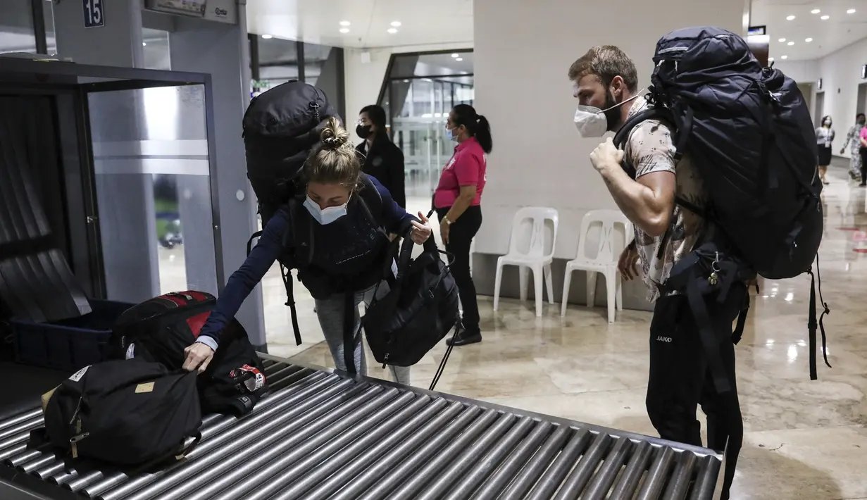 Turis dari Jerman membawa tas mereka saat mereka tiba di Bandara Internasional Manila, Filipina, Kamis (10/2/2022). Filipina mulai hari ini membuka kembali pintu bagi turis asing yang telah divaksinasi penuh Covid-19 setelah hampir dua tahun menutup perbatasannya. (AP Photo/Basilio Sepe)
