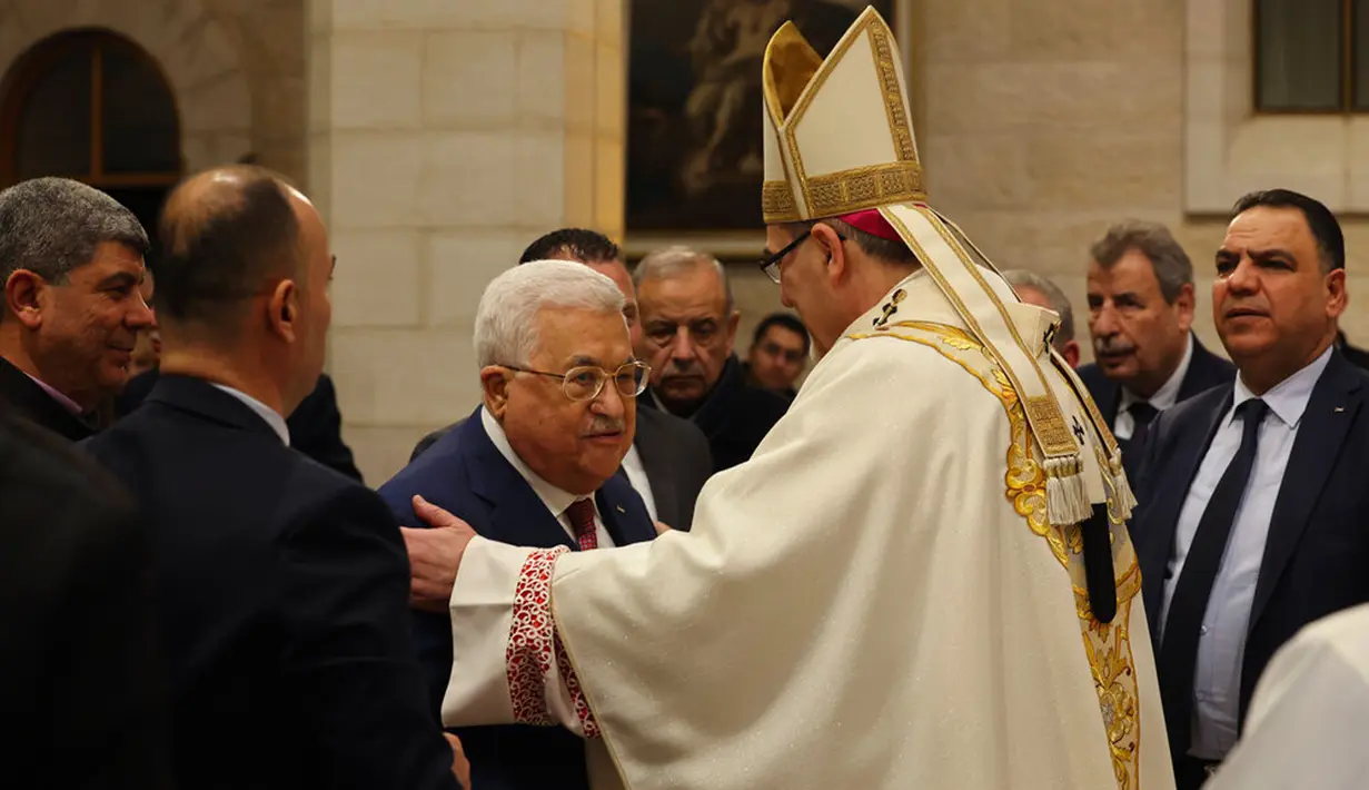 Presiden Palestina Mahmoud Abbas (tengah) mengucapkan selamat kepada Uskup Agung Pierbattista Pizzaballa, administrator apostolik Patriark Latin Yerusalem, dalam Misa Malam Natal di Kompleks Gereja Kelahiran Yesus, Bethlehem, Tepi Barat, Minggu (25/12/2022). Setelah dua tahun tutup karena COVID-19, jemaat kembali menghadiri ibadah tersebut kendati jumlahnya tidak sebanyak sebelum pandemi. (Ahmad Gharabli/Pool Photo via AP)