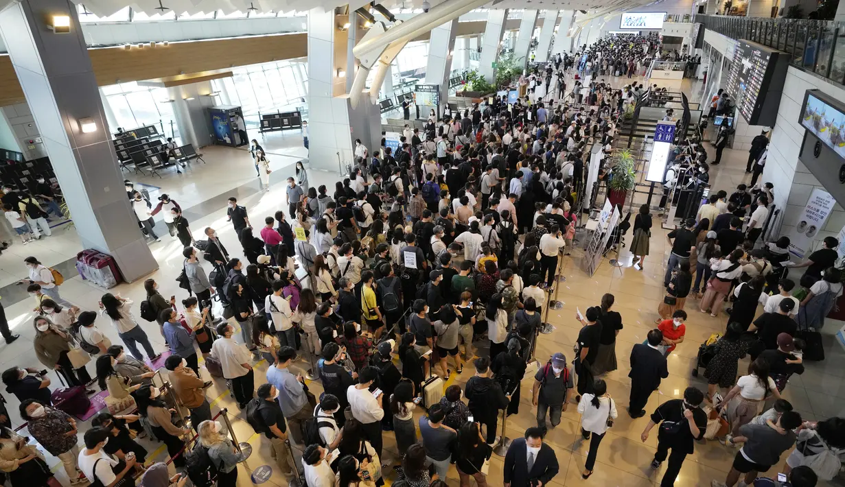 Penumpang yang mengenakan masker sebagai tindakan pencegahan terhadap virus corona berbaris untuk naik pesawat menjelang liburan Chuseok, Hari Thanksgiving versi Korea di terminal penerbangan domestik bandara Gimpo di Seoul, Korea Selatan (18/9/2021). (AP Photo/Ahn Young-joon)