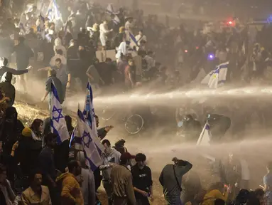 Polisi Israel menggunakan meriam air untuk membubarkan pengunjuk rasa yang memblokir jalan raya selama protes di Tel Aviv, Israel, Senin, 27 Maret 2023. (AP Photo/Oren Ziv)