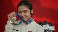 Peraih medali perunggu cabang olahraga bulu tangkis tunggal putri Olimpiade Paris 2024, Gregoria Mariska Tunjung berfoto dengan medali yang diraihnya di Istana Merdeka, Jakarta, pada Kamis 15 Agustus 2024. (BAY ISMOYO/AFP)