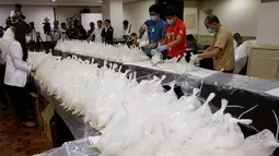 Petugas menata barang bukti penyelundupan narkoba di Kantor Biro Investigasi Nasional Filipina, Senin (29/5). Petugas Filipina menyita 600 kilogram metamfetamin yang diselundupkan dari China dengan nilai sekitar USD 121,4 juta. (AP Photo/Aaron Favila)
